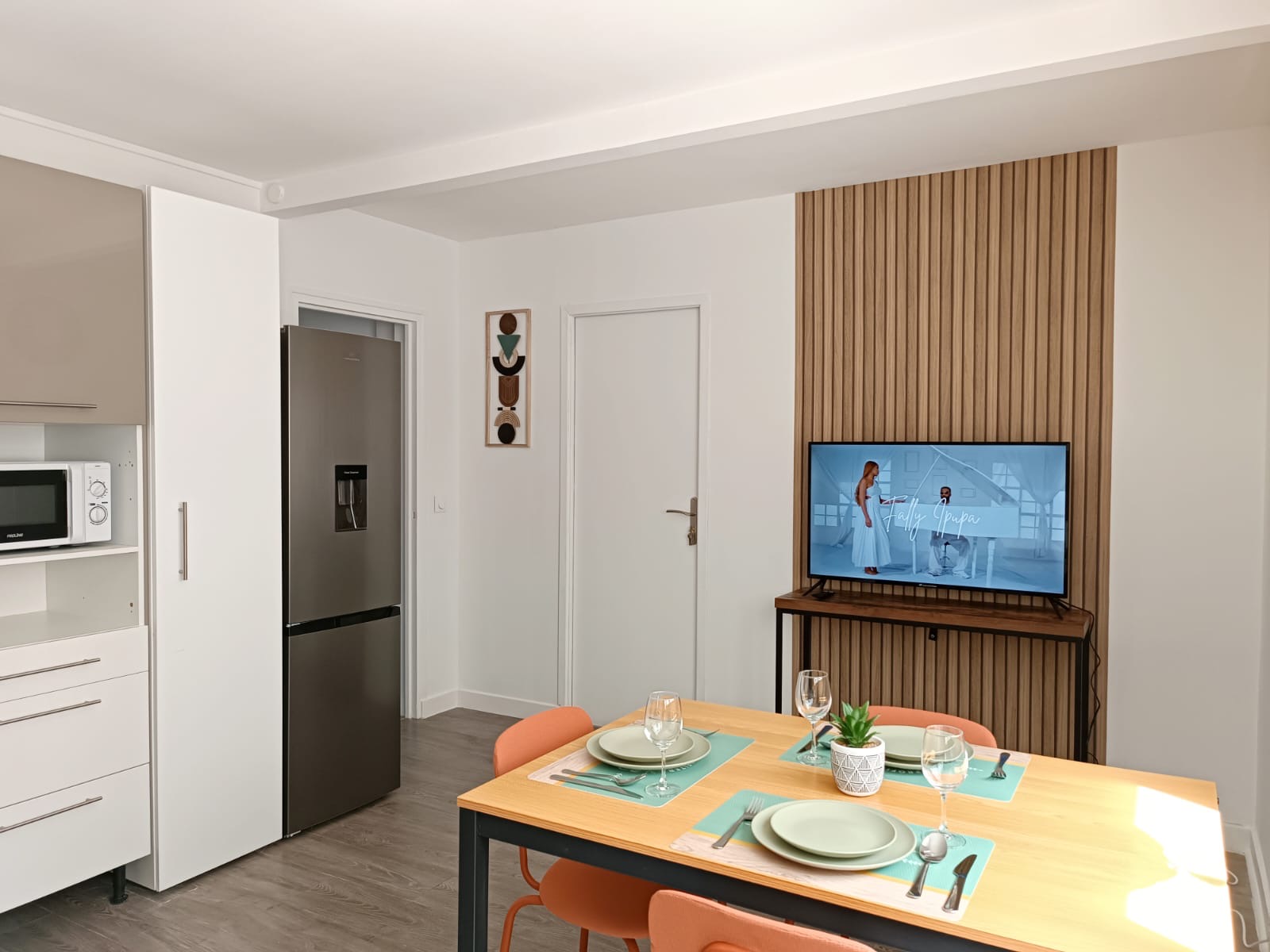 Salle à manger et coin télévision devant un mur en tasseaux de bois