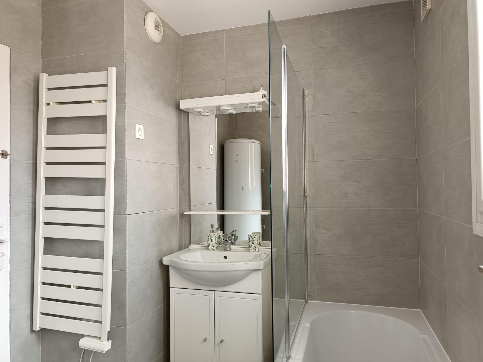Salle de bain avec sèche-serviettes, meuble vasque et douche