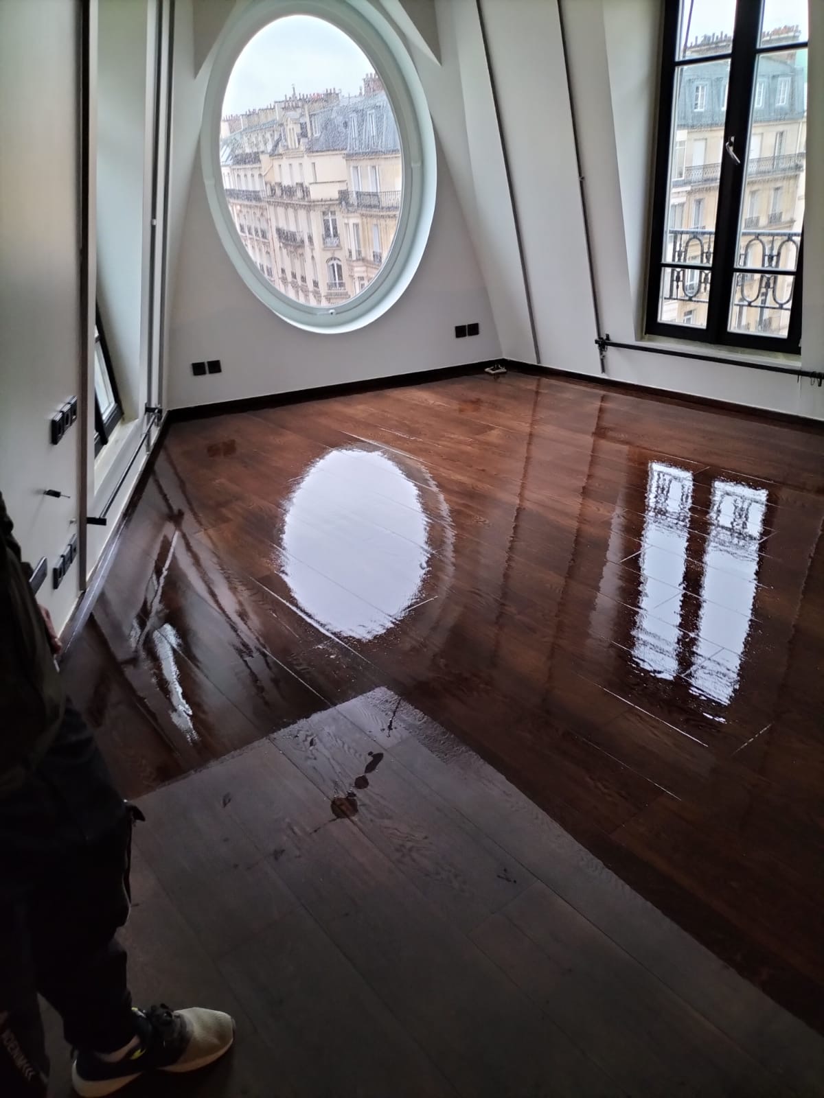 Parquet ancien vitrifié dans une pièce avec fenêtre ovale